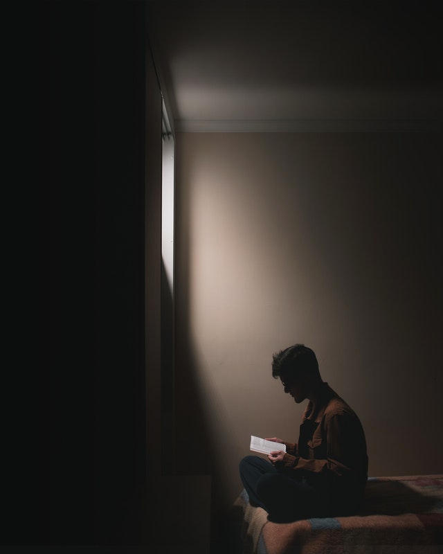man sitting in a shaft of light reading
